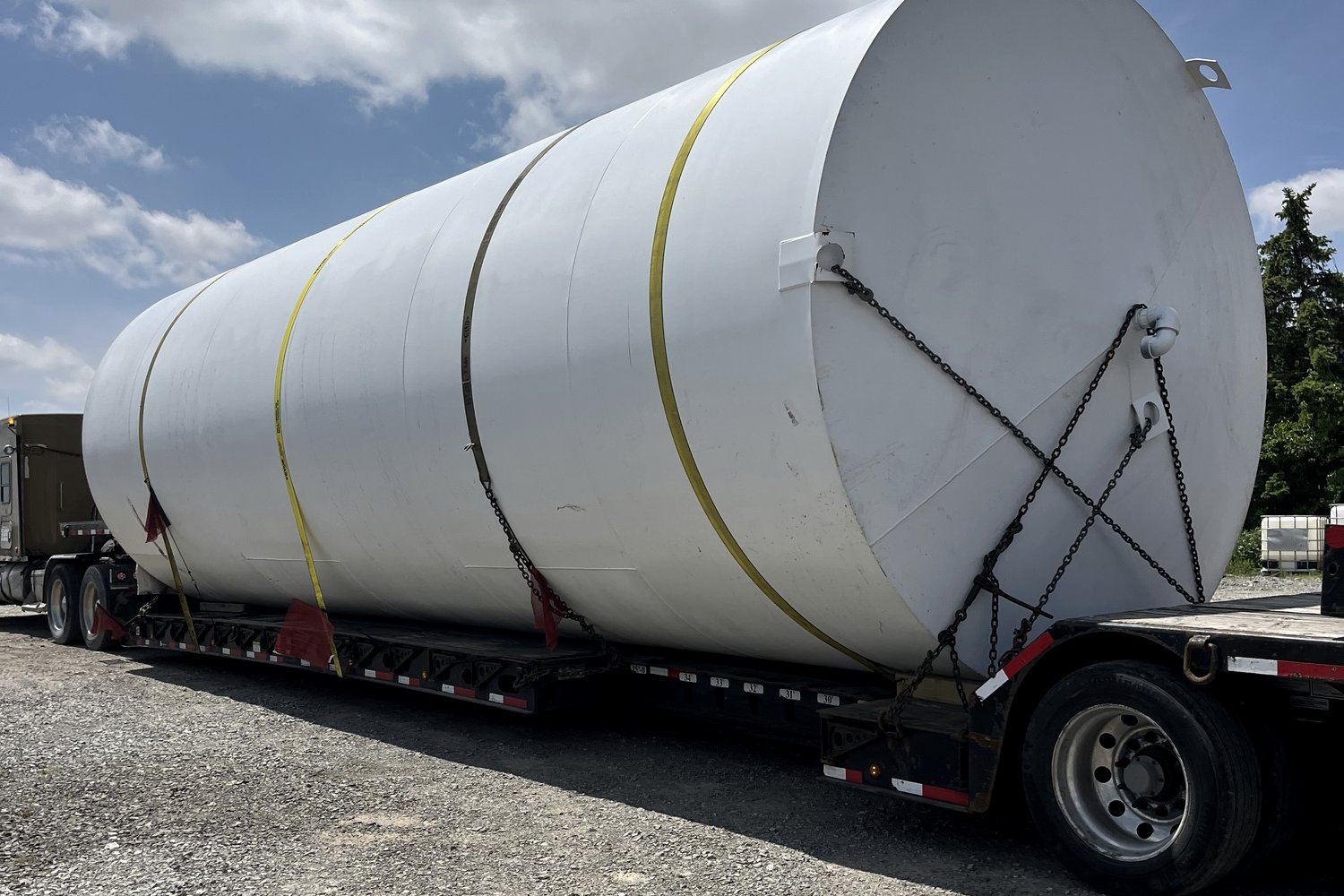 Oversized storage tank chained down on a step-deck trailer for heavy haul transport