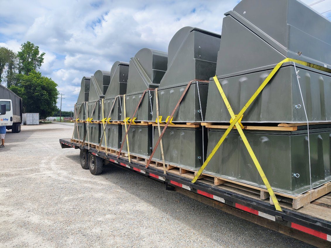 Skid-mounted industrial equipment chained and strapped to a flatbed trailer with edge protection