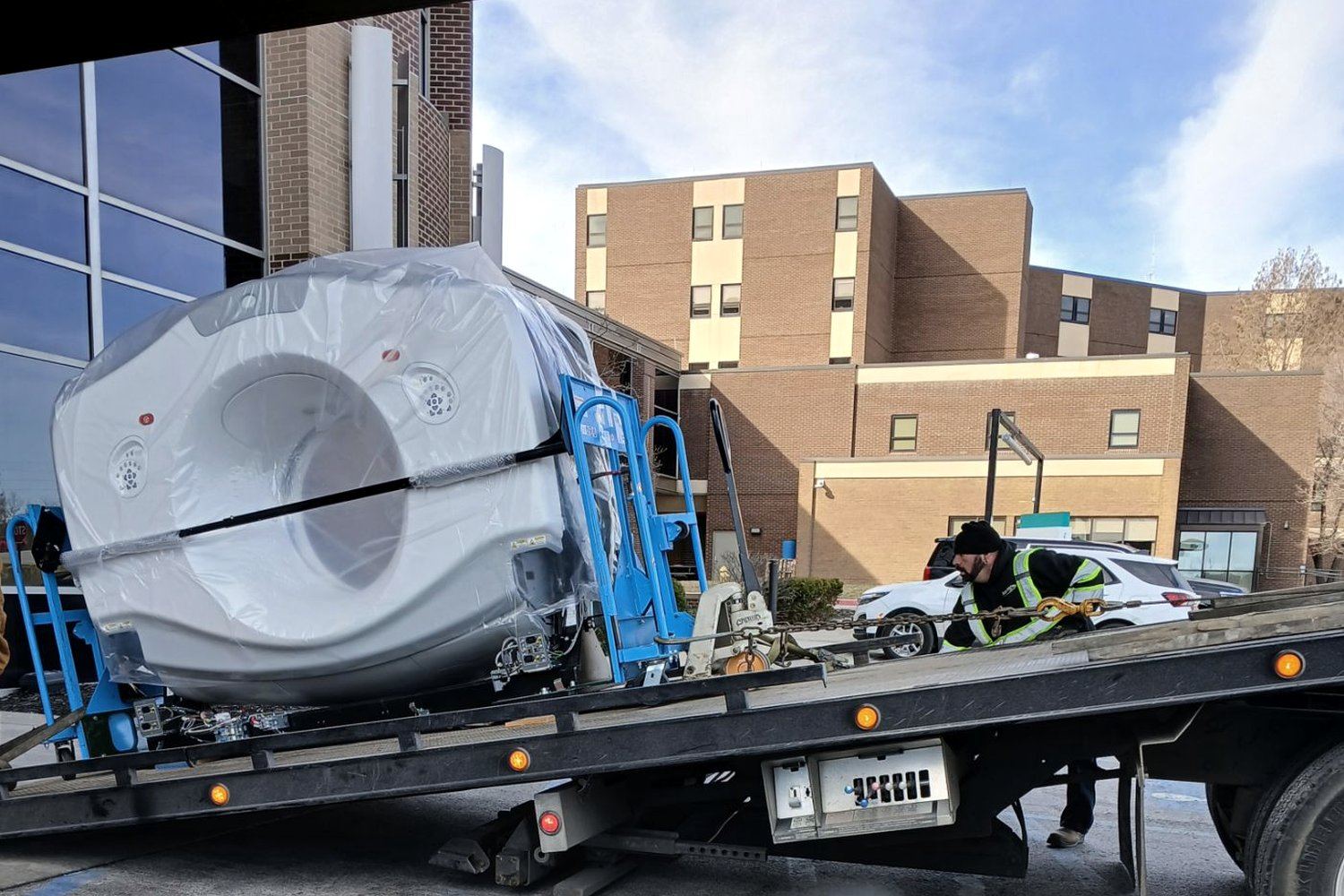 MRI scanner shrink-wrapped and secured on a flatbed during a Badass Logistics rigging and transport job at a hospital